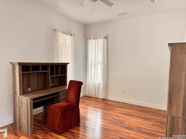 office space featuring ceiling fan, visible vents, baseboards, and wood finished floors