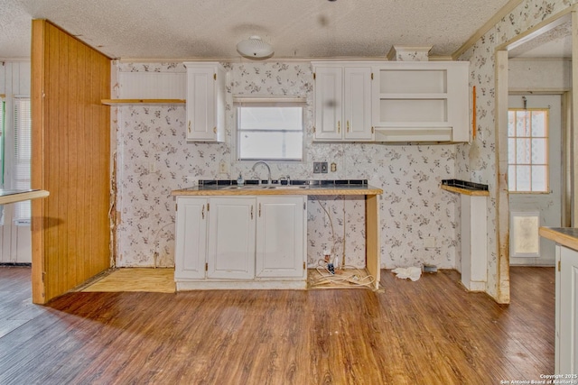 225 County Road 3821, San Antonio, TX 78253 - kitchen with a textured ceiling, a sink, white cabinets, light wood finished floors, and wallpapered walls