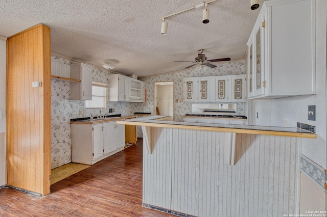 225 County Road 3821, San Antonio, TX 78253 - kitchen featuring a peninsula, white cabinets, a kitchen bar, glass insert cabinets, and wallpapered walls