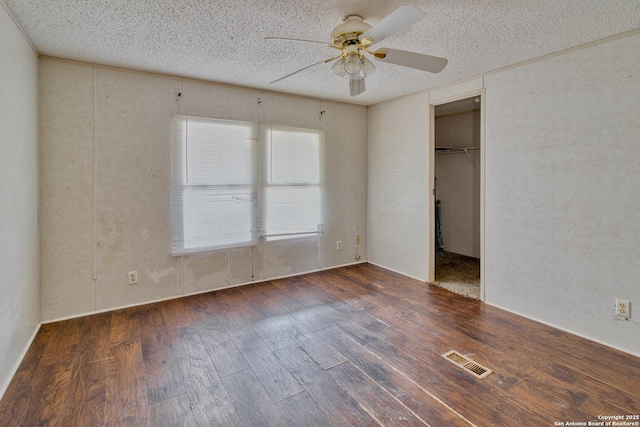 225 County Road 3821, San Antonio, TX 78253 - unfurnished bedroom with visible vents, a ceiling fan, dark wood-type flooring, a walk in closet, and a textured ceiling