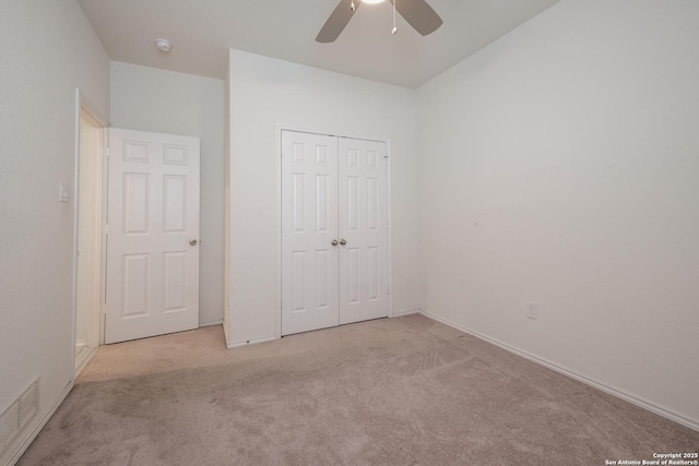 unfurnished bedroom featuring a ceiling fan, visible vents, a closet, and light colored carpet