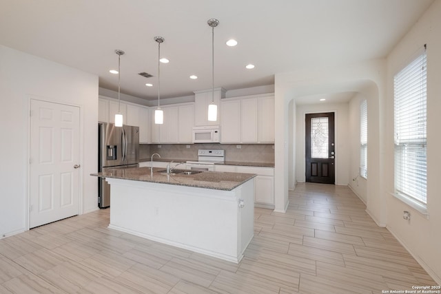 kitchen featuring a kitchen island with sink, white appliances, a sink, visible vents, and white cabinetry