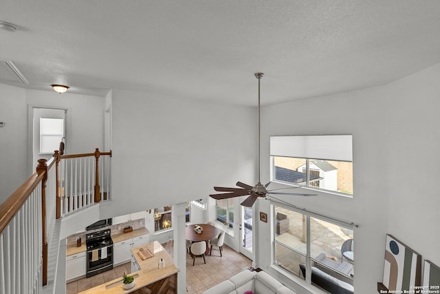 interior space with a textured ceiling, ceiling fan, and attic access