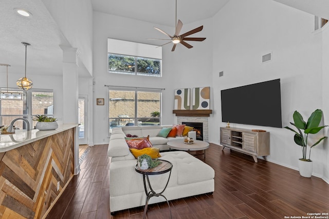 living area featuring wood tiled floor, a fireplace, visible vents, and a wealth of natural light