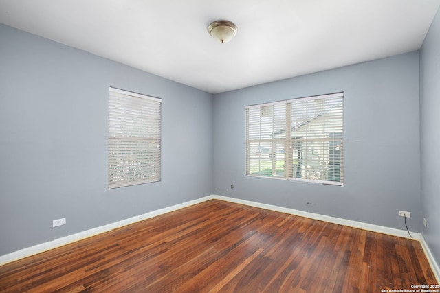 empty room with dark wood-style flooring and baseboards