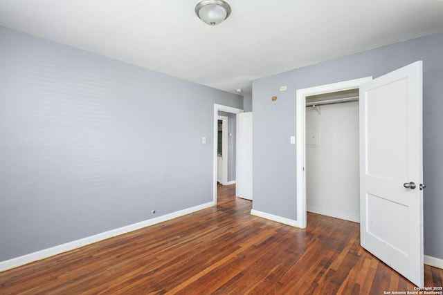 unfurnished bedroom with dark wood-style floors, a closet, and baseboards