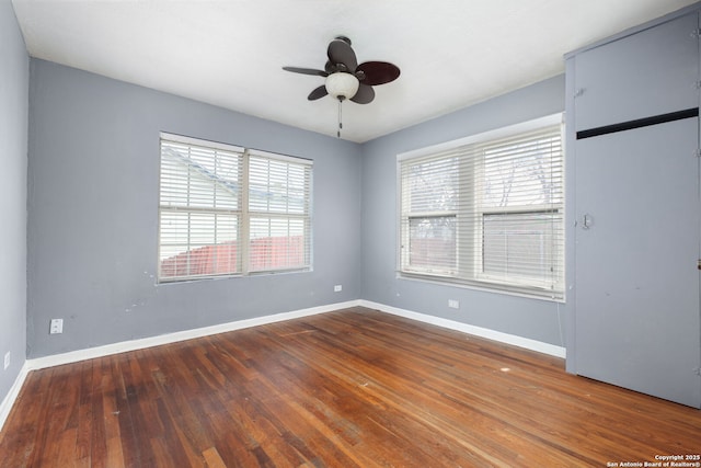 empty room with wood finished floors, a ceiling fan, and baseboards