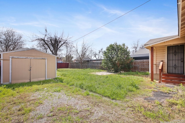 view of yard with entry steps, a fenced backyard, an outdoor structure, and a shed