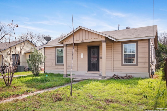 bungalow with central air condition unit, a front lawn, and board and batten siding