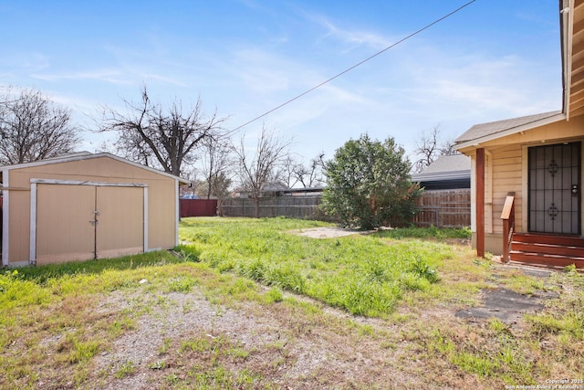 view of yard featuring entry steps, a fenced backyard, a storage unit, and an outdoor structure