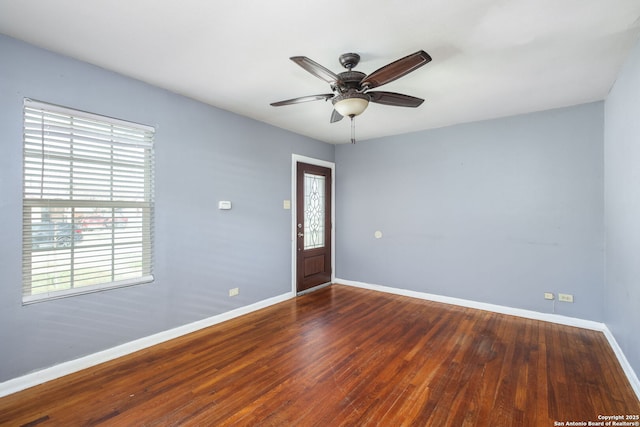 spare room featuring a ceiling fan, baseboards, and wood finished floors