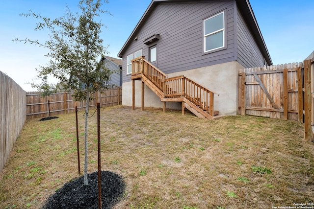 back of property featuring a yard, stairway, a fenced backyard, and a gate