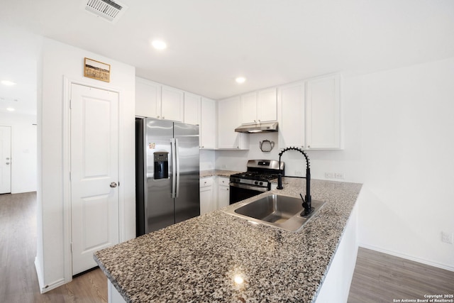 kitchen with under cabinet range hood, a peninsula, visible vents, white cabinetry, and appliances with stainless steel finishes