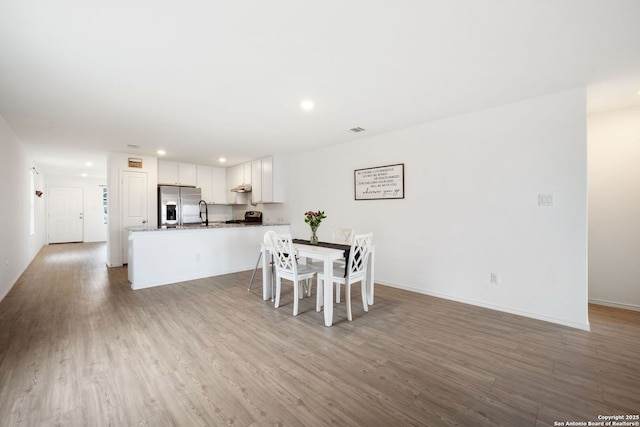 dining room with light wood finished floors, baseboards, and recessed lighting