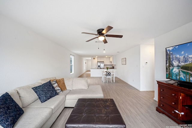 living area featuring light wood finished floors, visible vents, baseboards, and a ceiling fan