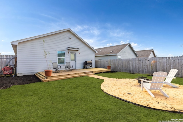 back of property with a fenced backyard, a deck, and a lawn