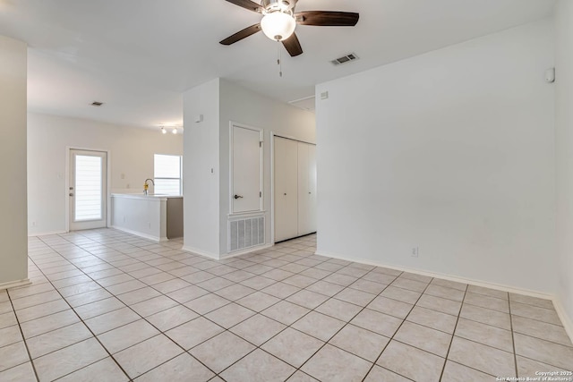 empty room with light tile patterned floors, baseboards, visible vents, and a ceiling fan