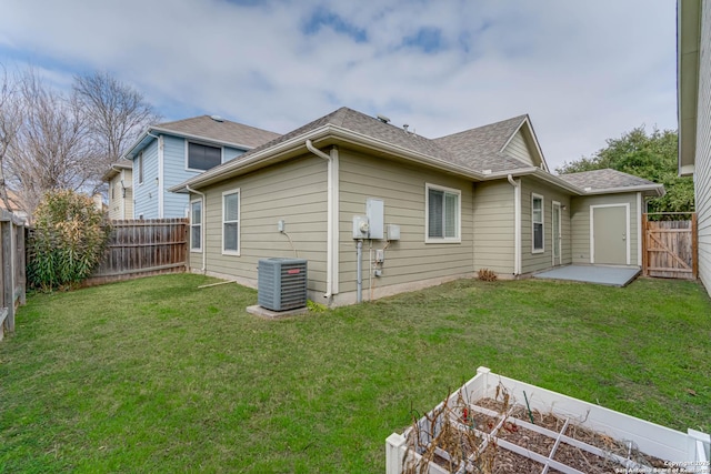 rear view of property featuring a fenced backyard, a vegetable garden, cooling unit, and a yard