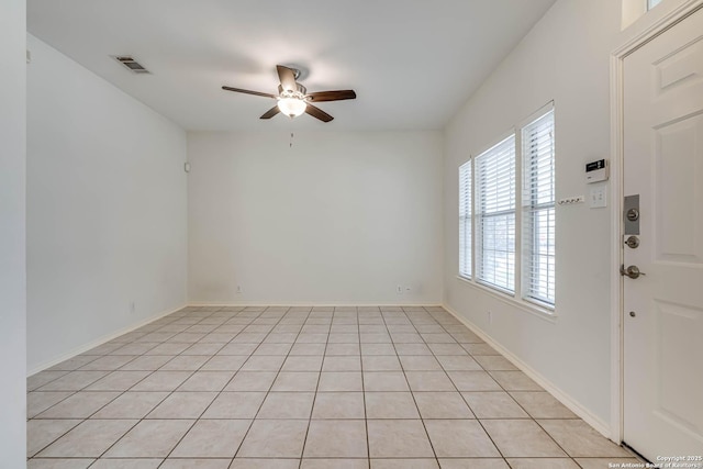 empty room with light tile patterned floors, baseboards, visible vents, and a ceiling fan