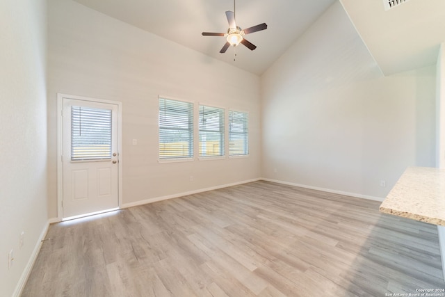 unfurnished living room with ceiling fan, high vaulted ceiling, light wood-type flooring, and baseboards