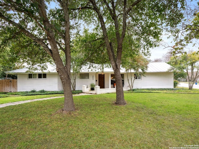 view of front facade with metal roof, fence, a front lawn, and brick siding