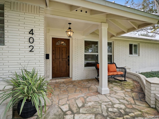 property entrance with brick siding and a porch