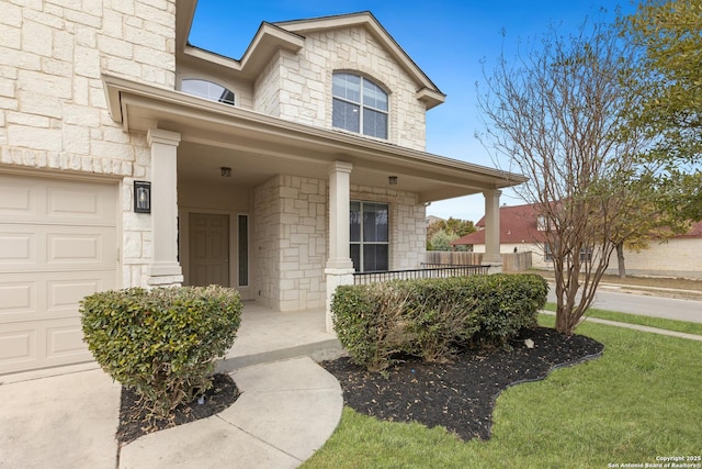 property entrance featuring a garage, stone siding, and a porch