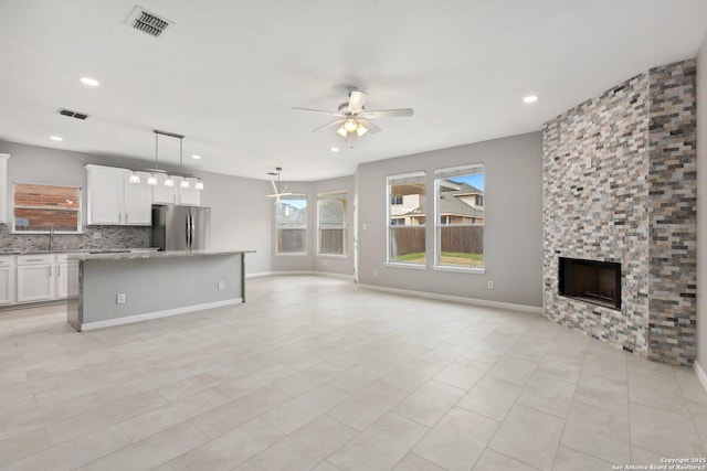 unfurnished living room featuring a fireplace, recessed lighting, a sink, ceiling fan, and baseboards