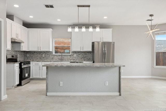 kitchen featuring hanging light fixtures, appliances with stainless steel finishes, a kitchen island, and light stone countertops