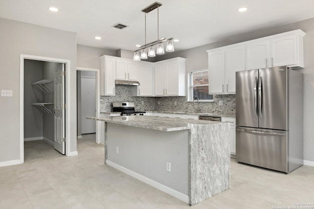 kitchen with decorative light fixtures, stainless steel appliances, visible vents, white cabinetry, and a kitchen island