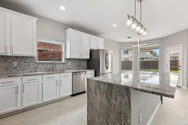 kitchen with stainless steel appliances, decorative light fixtures, white cabinetry, and a center island