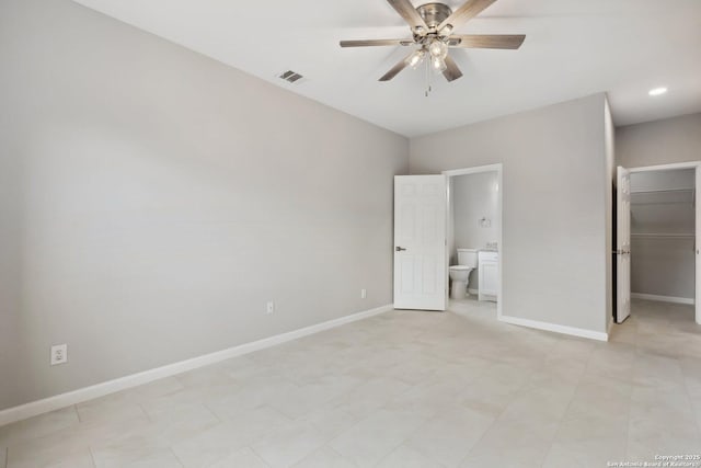 unfurnished bedroom featuring a walk in closet, visible vents, connected bathroom, and baseboards