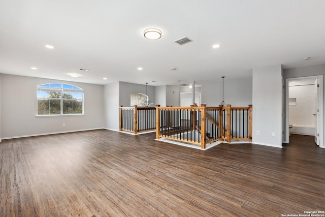 empty room with a notable chandelier, baseboards, visible vents, and dark wood-type flooring