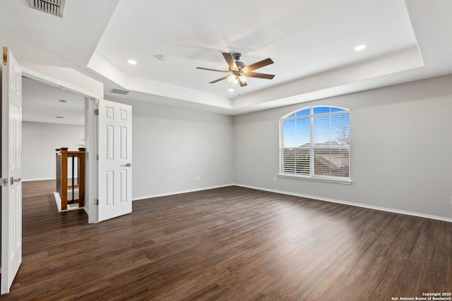 spare room featuring dark wood-style floors, ceiling fan, a raised ceiling, and visible vents