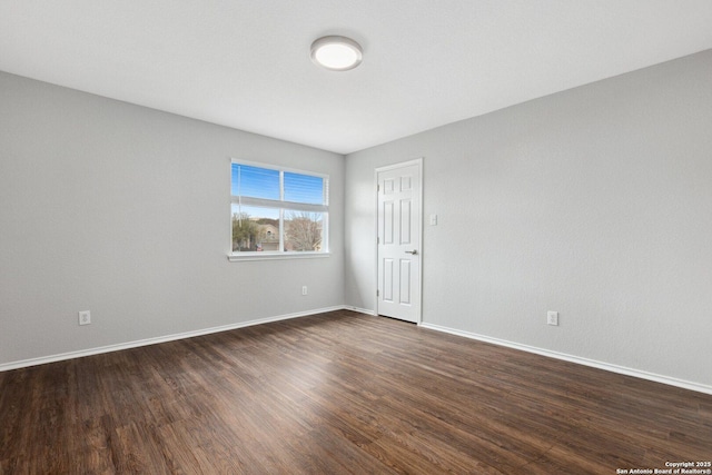 unfurnished room with dark wood-style flooring and baseboards