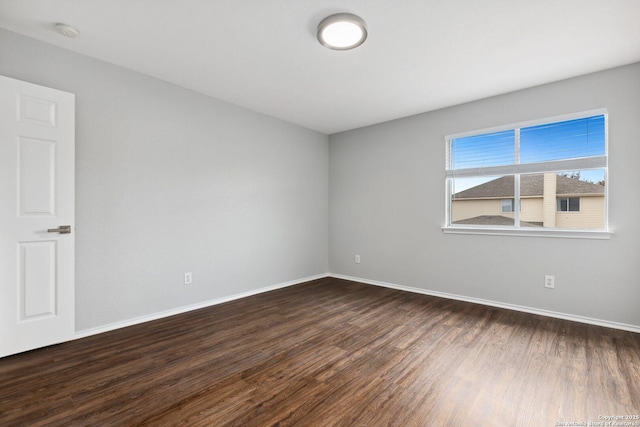 empty room featuring baseboards and dark wood finished floors