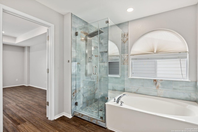 bathroom with recessed lighting, a stall shower, wood finished floors, baseboards, and a bath