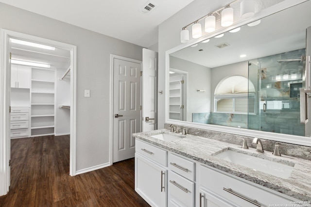 full bathroom with a spacious closet, a stall shower, a sink, and visible vents