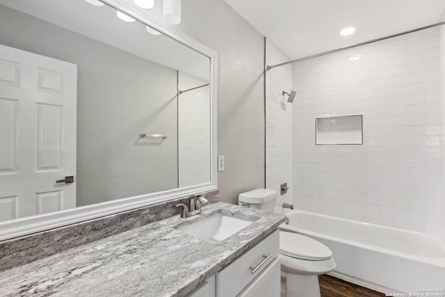 bathroom with toilet,  shower combination, wood finished floors, and vanity