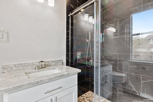 full bathroom with toilet, a textured wall, a marble finish shower, and vanity