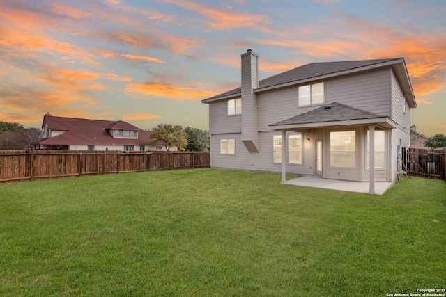 rear view of house featuring a chimney, a patio area, a lawn, and a fenced backyard