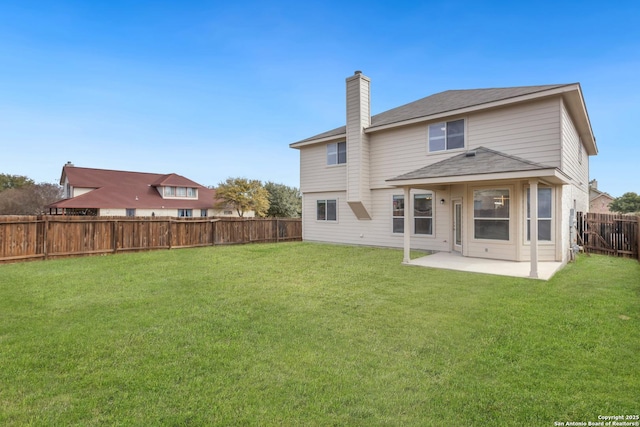 rear view of house with a chimney, a patio area, a fenced backyard, and a lawn