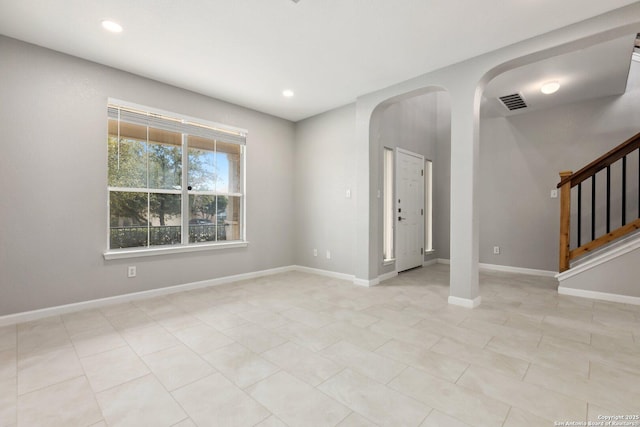 unfurnished room with arched walkways, stairway, baseboards, and recessed lighting