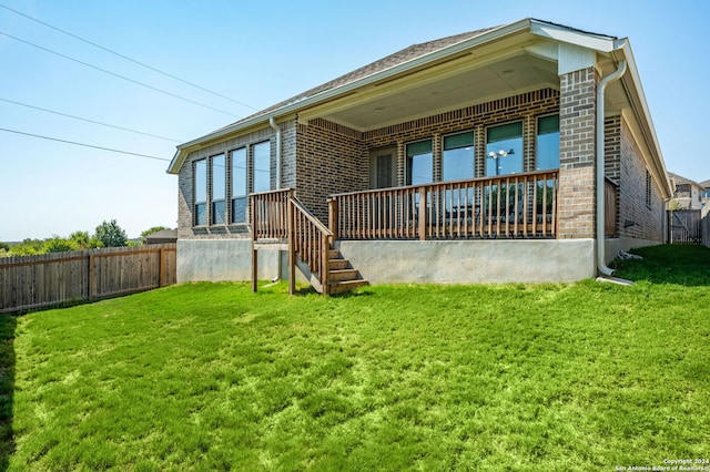 rear view of property featuring a yard, brick siding, and fence