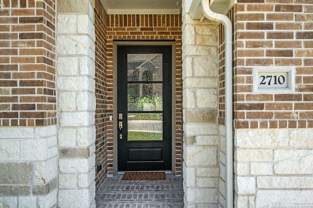 view of exterior entry featuring stone siding and brick siding