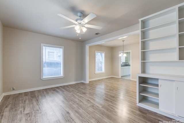 spare room with ceiling fan, wood finished floors, visible vents, and baseboards