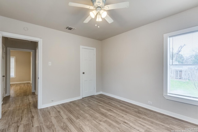 unfurnished room featuring light wood-style flooring, a ceiling fan, visible vents, and baseboards