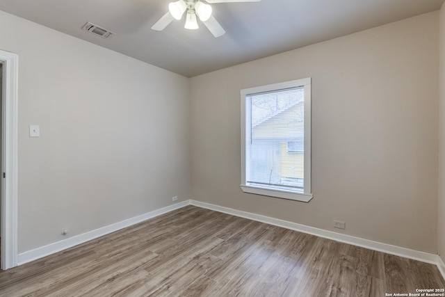 spare room featuring light wood-style floors, visible vents, ceiling fan, and baseboards