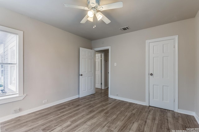 unfurnished bedroom with a ceiling fan, light wood-type flooring, visible vents, and baseboards