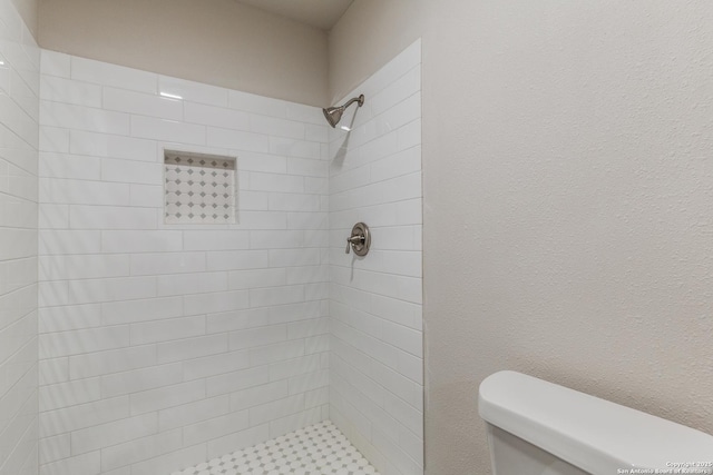 bathroom with toilet and tiled shower